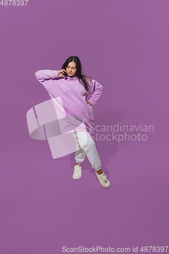 Image of High angle view of young woman on purple studio background. Girl in motion or movement. Human emotions and facial expressions concept