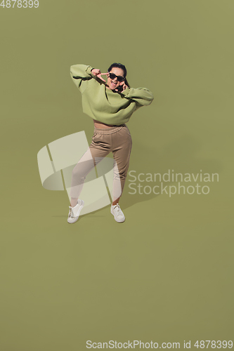 Image of High angle view of young woman on green studio background. Girl in motion or movement. Human emotions and facial expressions concept