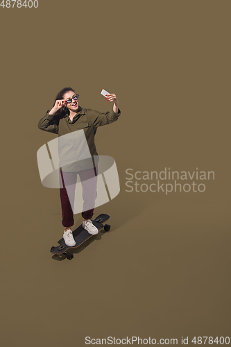 Image of High angle view of young woman on brown studio background. Girl in motion or movement. Human emotions and facial expressions concept