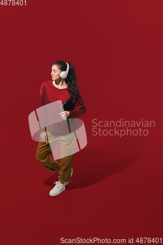 Image of High angle view of young woman on red studio background. Girl in motion or movement. Human emotions and facial expressions concept