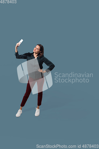 Image of High angle view of young woman on blue studio background. Girl in motion or movement. Human emotions and facial expressions concept