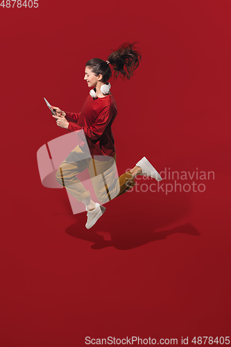 Image of High angle view of young woman on red studio background. Girl in motion or movement. Human emotions and facial expressions concept