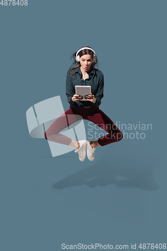 Image of High angle view of young woman on blue studio background. Girl in motion or movement. Human emotions and facial expressions concept