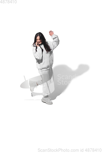 Image of High angle view of young woman on white studio background. Girl in motion or movement. Human emotions and facial expressions concept