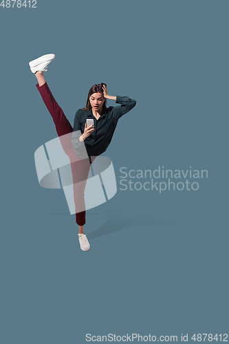 Image of High angle view of young woman on blue studio background. Girl in motion or movement. Human emotions and facial expressions concept