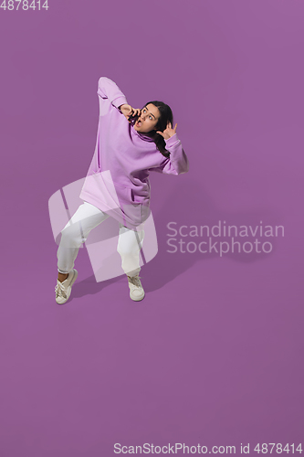 Image of High angle view of young woman on purple studio background. Girl in motion or movement. Human emotions and facial expressions concept