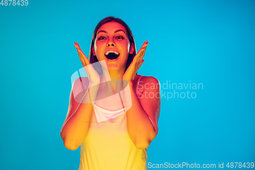 Image of Caucasian young woman\'s portrait isolated on blue background in neon light