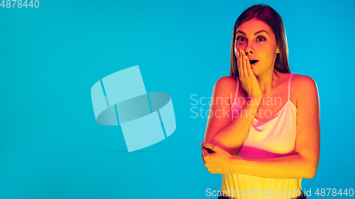 Image of Caucasian young woman\'s portrait isolated on blue background in neon light
