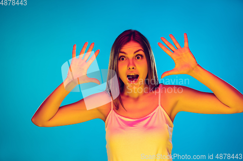 Image of Caucasian young woman\'s portrait isolated on blue background in neon light