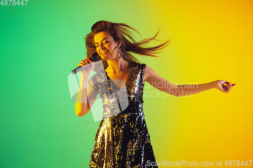 Image of Caucasian female singer portrait isolated on gradient studio background in neon light