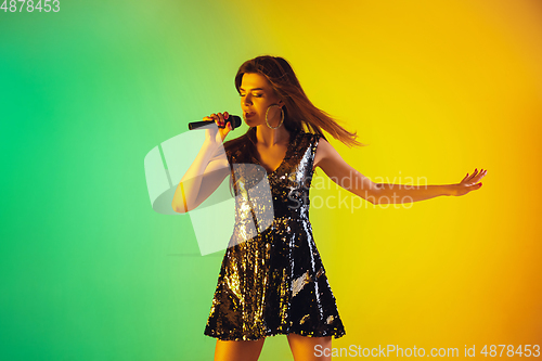 Image of Caucasian female singer portrait isolated on gradient studio background in neon light