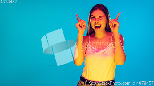 Image of Caucasian young woman\'s portrait isolated on blue background in neon light