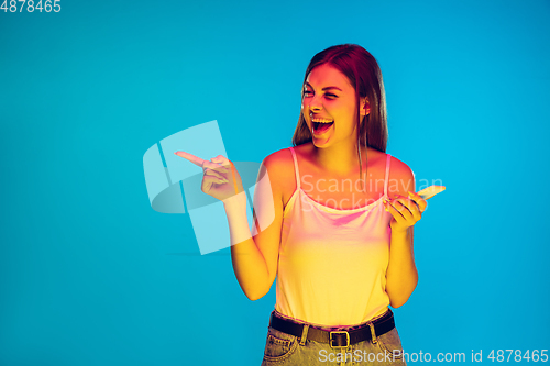 Image of Caucasian young woman\'s portrait isolated on blue background in neon light