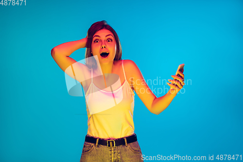Image of Caucasian young woman\'s portrait isolated on blue background in neon light
