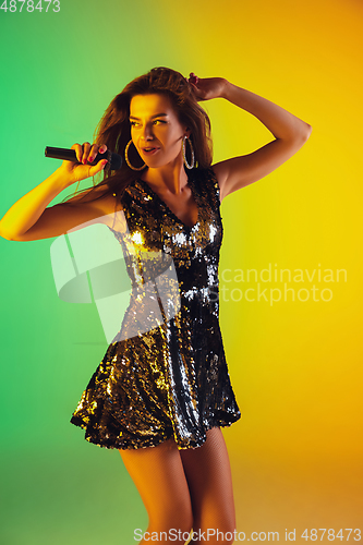 Image of Caucasian female singer portrait isolated on gradient studio background in neon light