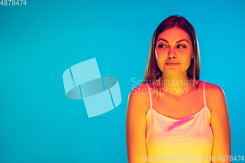 Image of Caucasian young woman\'s portrait isolated on blue background in neon light