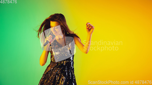 Image of Caucasian female singer portrait isolated on gradient studio background in neon light