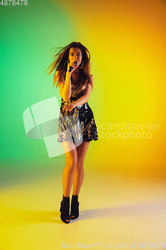 Image of Caucasian female singer portrait isolated on gradient studio background in neon light