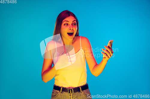 Image of Caucasian young woman\'s portrait isolated on blue background in neon light