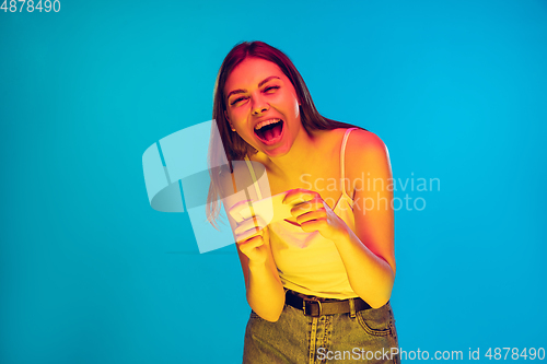 Image of Caucasian young woman\'s portrait isolated on blue background in neon light
