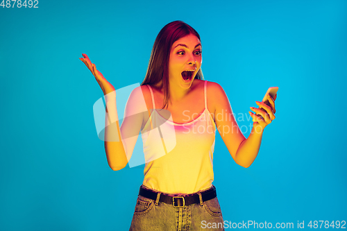 Image of Caucasian young woman\'s portrait isolated on blue background in neon light