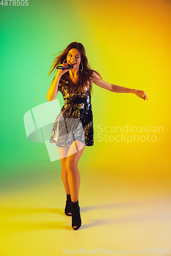 Image of Caucasian female singer portrait isolated on gradient studio background in neon light