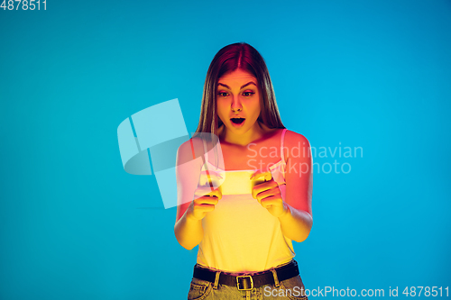 Image of Caucasian young woman\'s portrait isolated on blue background in neon light