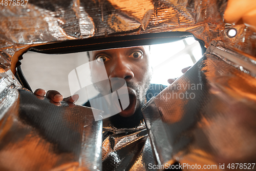 Image of African-american man looking for job in unusual places at his home