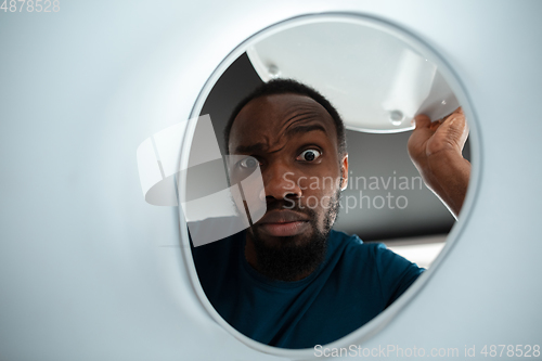 Image of African-american man looking for job in unusual places at his home