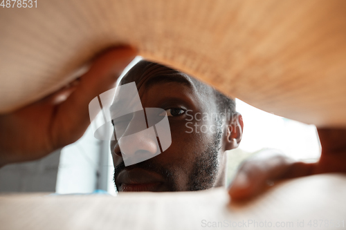 Image of African-american man looking for job in unusual places at his home