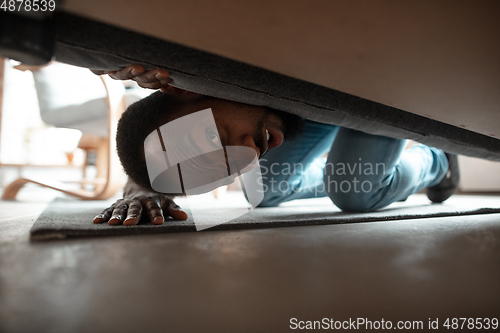 Image of African-american man looking for job in unusual places at his home