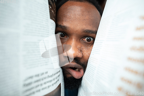 Image of African-american man looking for job in unusual places at his home