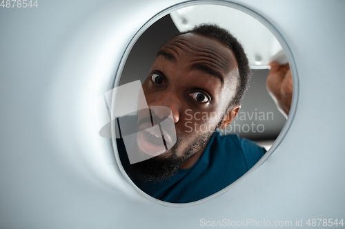 Image of African-american man looking for job in unusual places at his home