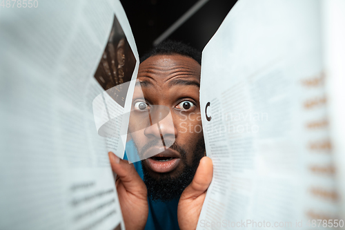 Image of African-american man looking for job in unusual places at his home