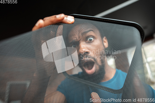 Image of African-american man looking for job in unusual places at his home