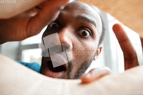 Image of African-american man looking for job in unusual places at his home