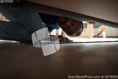 Image of African-american man looking for job in unusual places at his home