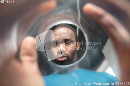 Image of African-american man looking for job in unusual places at his home