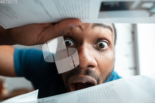 Image of African-american man looking for job in unusual places at his home