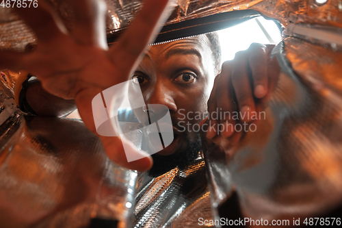 Image of African-american man looking for job in unusual places at his home