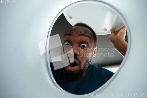 Image of African-american man looking for job in unusual places at his home