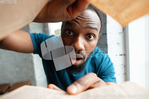 Image of African-american man looking for job in unusual places at his home