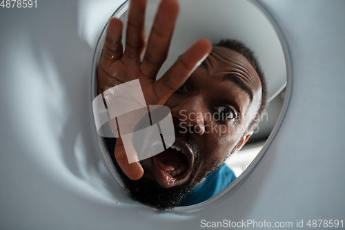 Image of African-american man looking for job in unusual places at his home