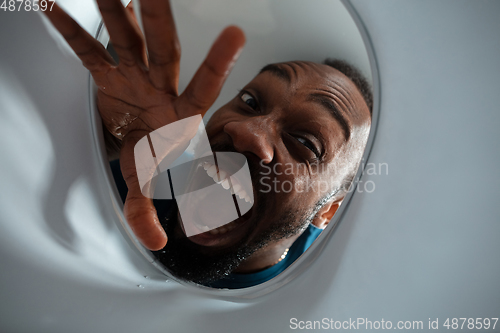 Image of African-american man looking for job in unusual places at his home