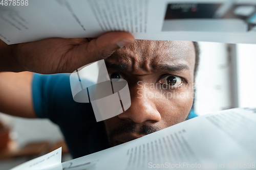 Image of African-american man looking for job in unusual places at his home