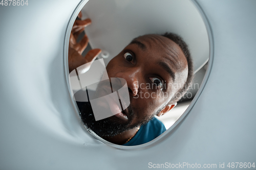 Image of African-american man looking for job in unusual places at his home