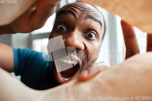 Image of African-american man looking for job in unusual places at his home