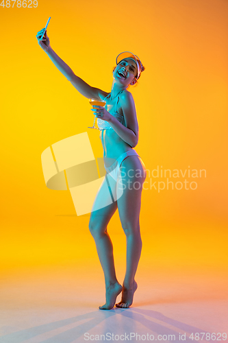 Image of Fashion portrait of seductive girl in stylish swimwear posing on a bright yellow background. Summertime, beach season