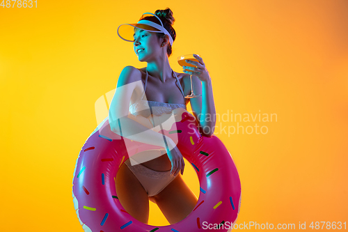 Image of Fashion portrait of seductive girl in stylish swimwear posing on a bright yellow background. Summertime, beach season