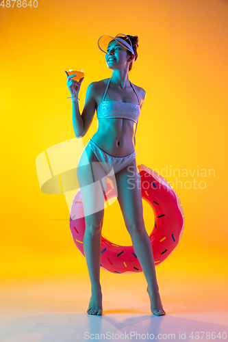 Image of Fashion portrait of seductive girl in stylish swimwear posing on a bright yellow background. Summertime, beach season